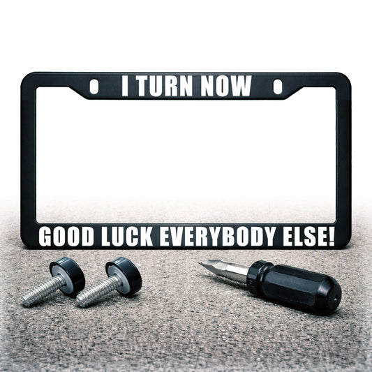 I Turn Now, Good Luck Everybody Else! license plate frame shown upright with mounting screws, black caps, and a mini screwdriver