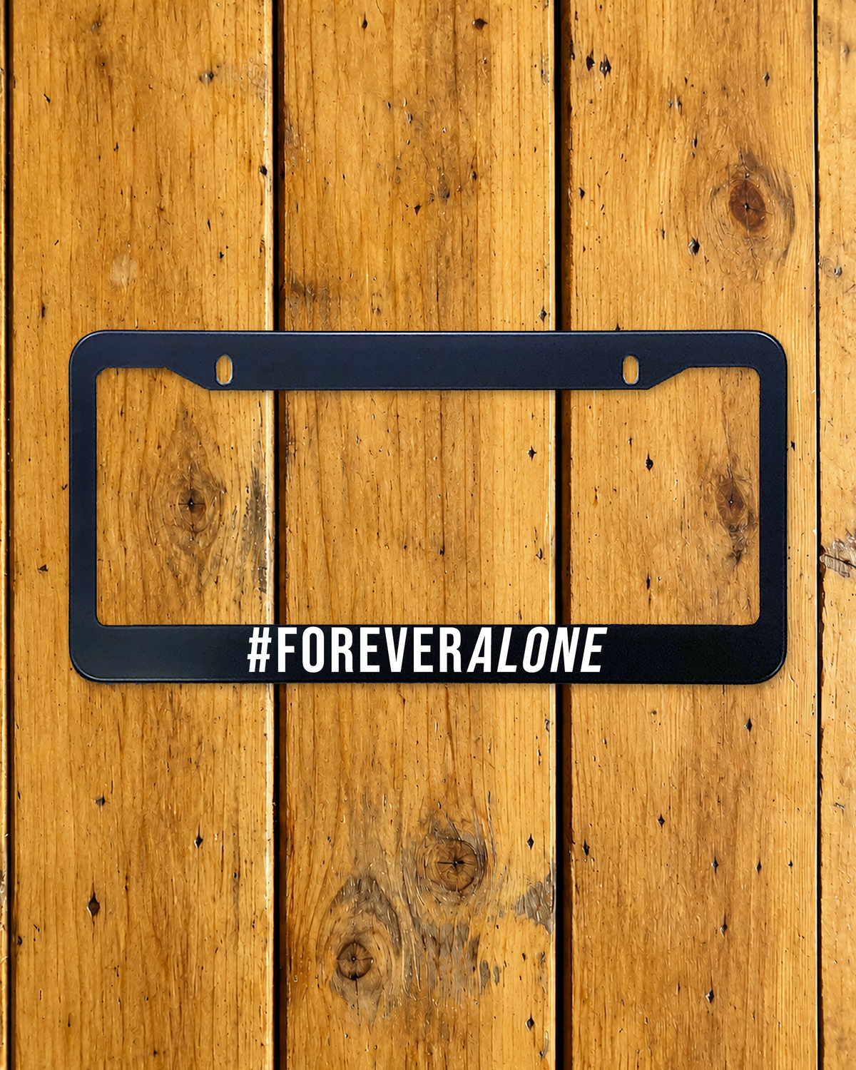 Forever Alone license plate frame shown on a warm wood background