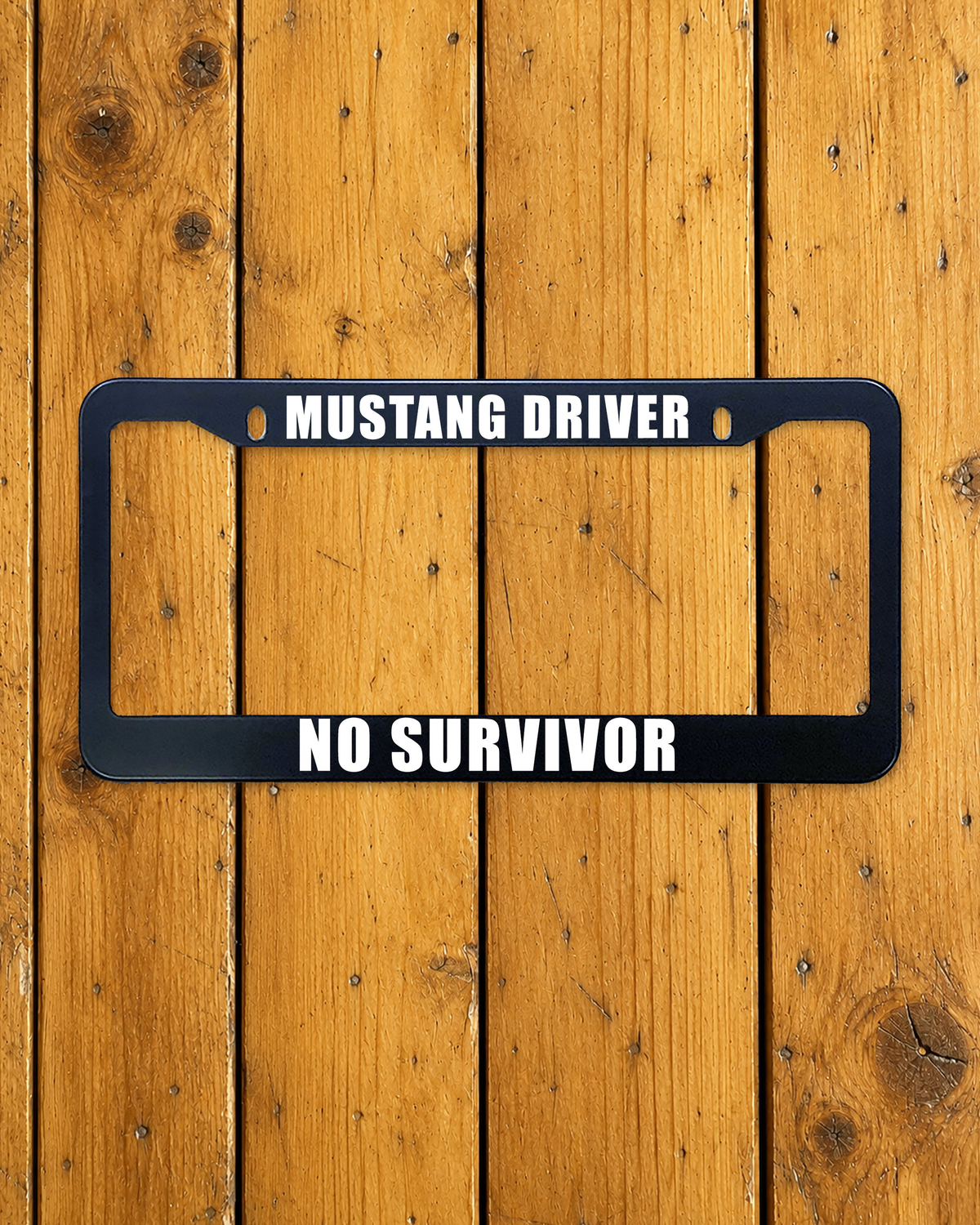 Mustang Driver, No Survivor license plate frame shown on a warm wood background